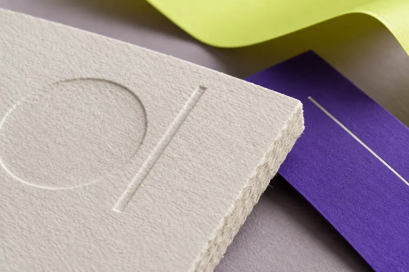 Concept close-up of textured cream paper with a recessed pattern, a silver foil line and purple stock